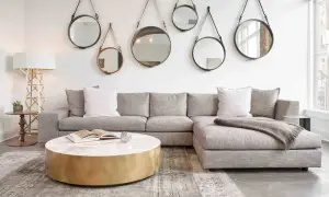 En soffgrupp med grå soffa, marmorbord och flera runda speglar på väggen skapar en elegant art deco inredning.