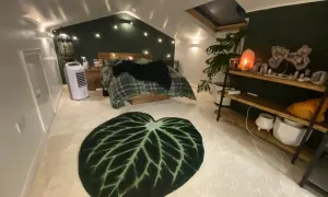 Sovrum med mysig cottage core-känsla. Rutiga sängkläder, gröna väggar och en stor bladmatta. Kristallampor och växter skapar en drömsk atmosfär.