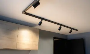Svart spotlightskena med flera justerbara lampor ger modern belysning hall inspiration. Ljuset träffar ljusa träskåp.