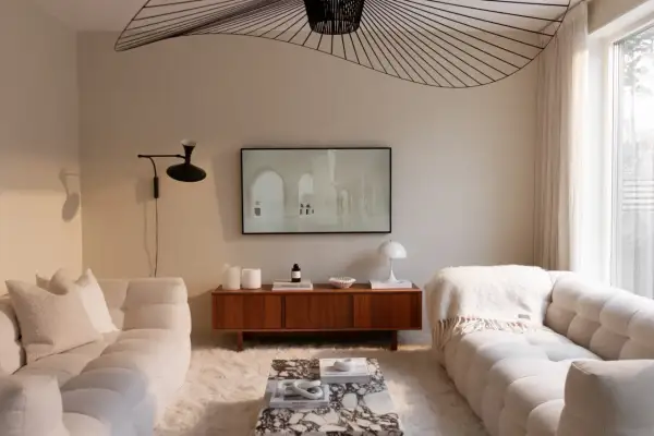 Vardagsrum inspiration beige med mjuka soffor, marmorbord och en konstnärlig taklampa.