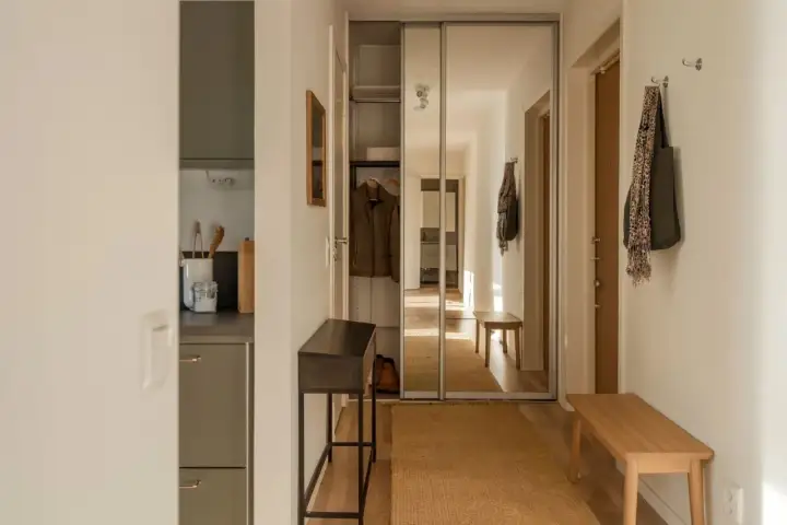 Hall med skjutdörrsgarderob med spegel, bänk och smal konsol. Bra rum tips för en hall.